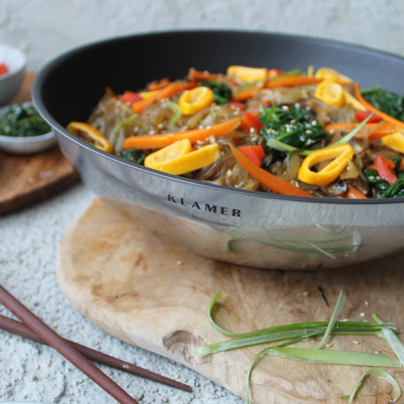 Profi Edelstahl-Wok 28cm with colorful vegetables served, showcasing heat distribution and non-stick features.
