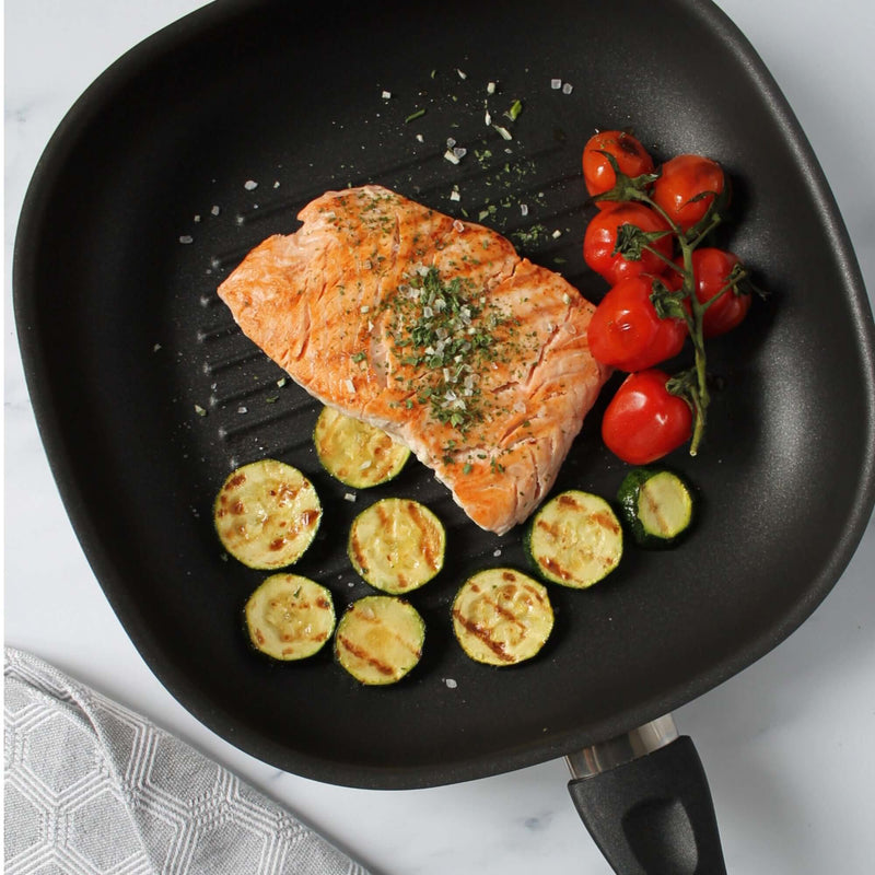 Grillpfanne 28cm with grilled salmon, zucchini slices, and cherry tomatoes, showcasing its non-stick surface.